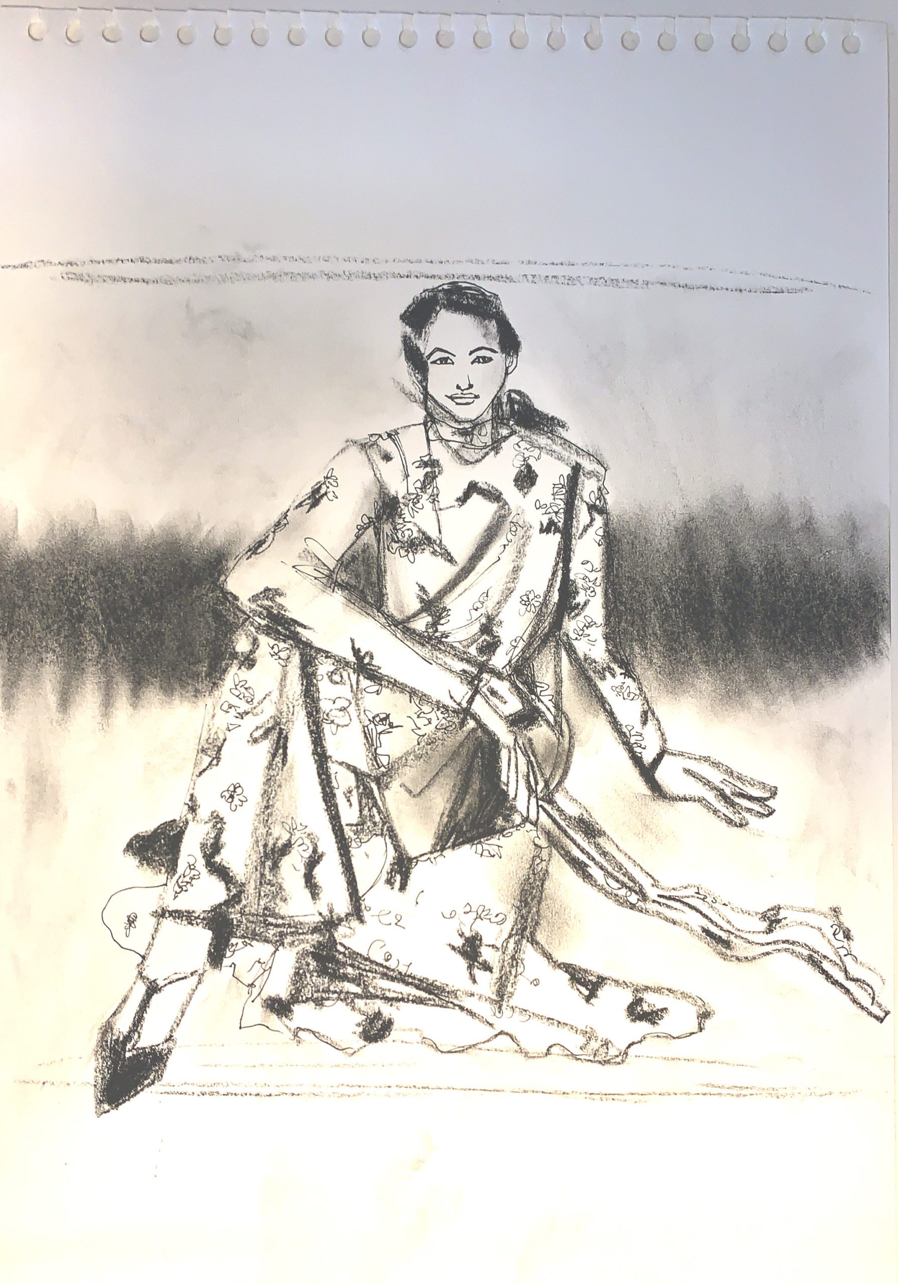 Charcoal fashion sketchbook drawing, seated model in patterned dress by Laura volpintesta